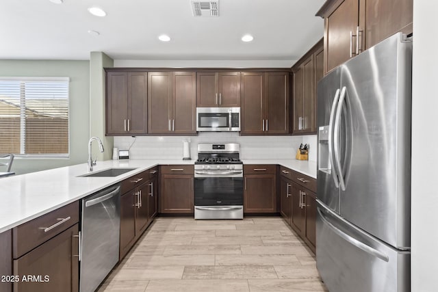 6919 S 13th Pl, Phoenix, AZ 85042 - kitchen featuring stainless steel appliances, light countertops, dark brown cabinets, decorative backsplash, and recessed lighting