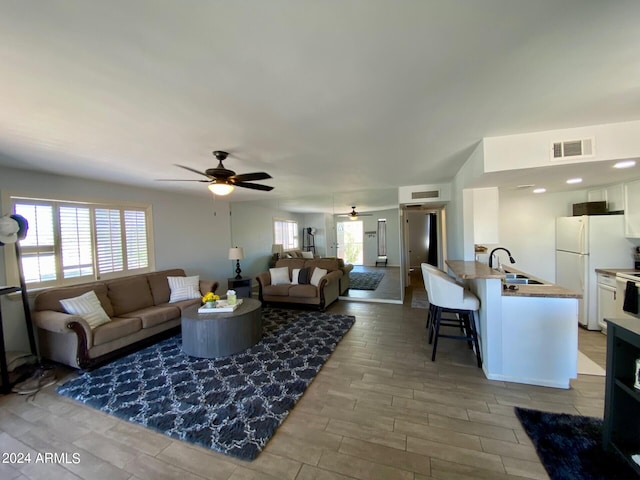 living room featuring light hardwood / wood-style flooring, sink, and ceiling fan