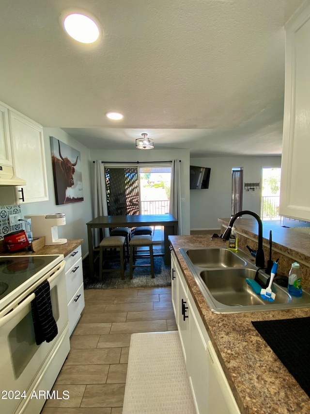 kitchen featuring extractor fan, white cabinets, sink, and white appliances