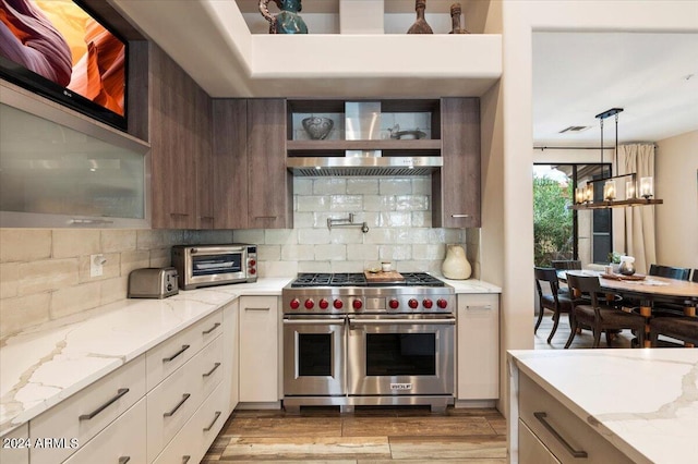 kitchen with a notable chandelier, light stone counters, light hardwood / wood-style flooring, and premium range