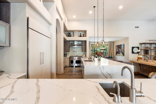 kitchen featuring pendant lighting, high end stove, light stone countertops, and dark wood-type flooring