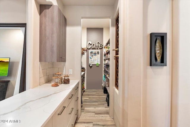 interior space with tasteful backsplash, light stone countertops, and light hardwood / wood-style flooring