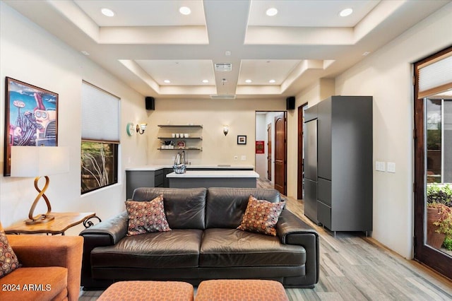 living room with light wood-type flooring, a wealth of natural light, and coffered ceiling