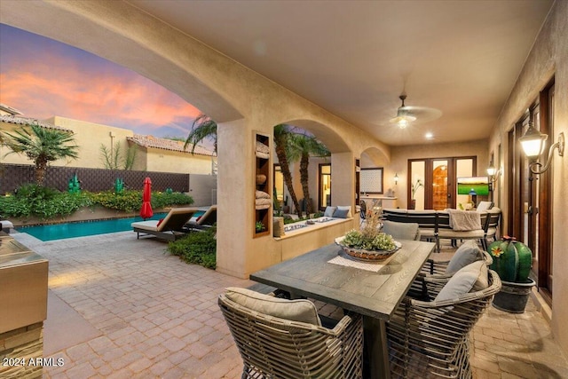 patio terrace at dusk featuring a fenced in pool and ceiling fan