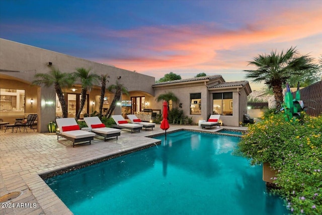 pool at dusk featuring a patio area