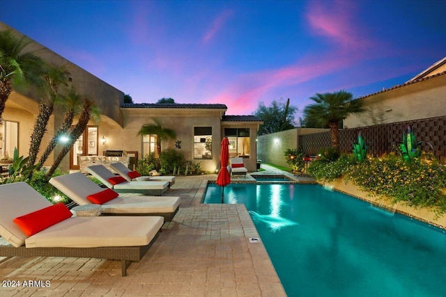 pool at dusk featuring a patio area and a jacuzzi