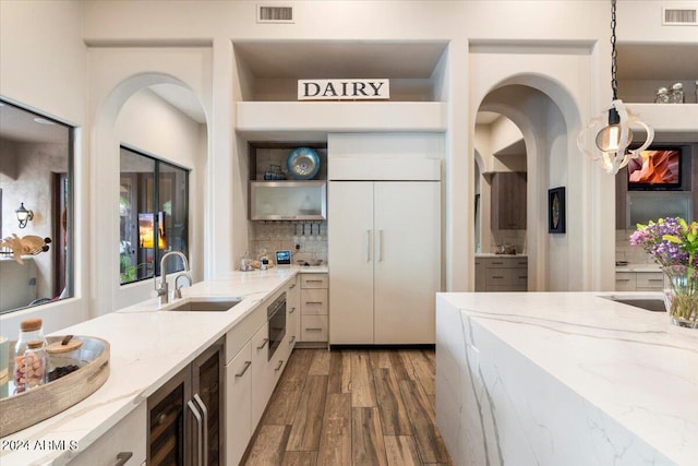 kitchen featuring light stone countertops, backsplash, sink, pendant lighting, and hardwood / wood-style floors