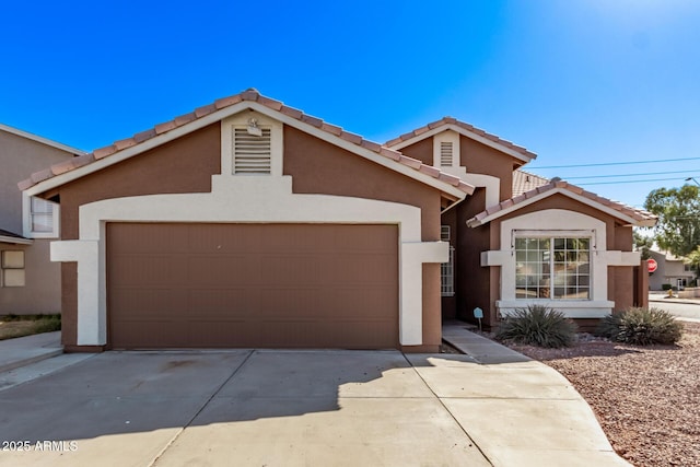 view of front facade with concrete driveway, a tiled roof, a garage, and stucco siding