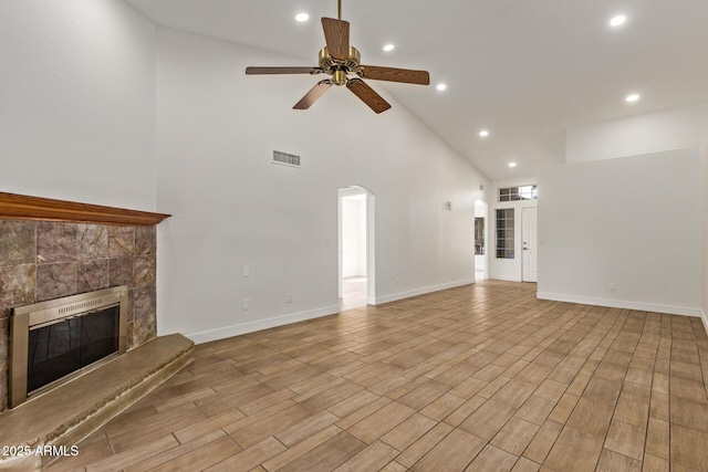 unfurnished living room featuring baseboards, visible vents, a tile fireplace, ceiling fan, and light wood-type flooring