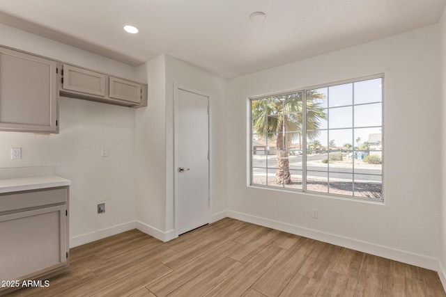 unfurnished dining area with recessed lighting, light wood-type flooring, and baseboards