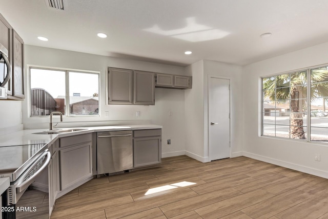 kitchen with a healthy amount of sunlight, gray cabinetry, stainless steel appliances, and a sink