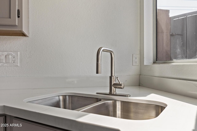 details featuring light countertops, a textured wall, and a sink