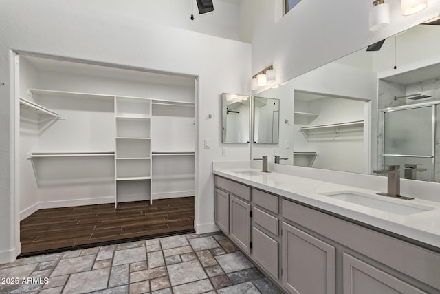 bathroom featuring a sink, a shower stall, a ceiling fan, and double vanity