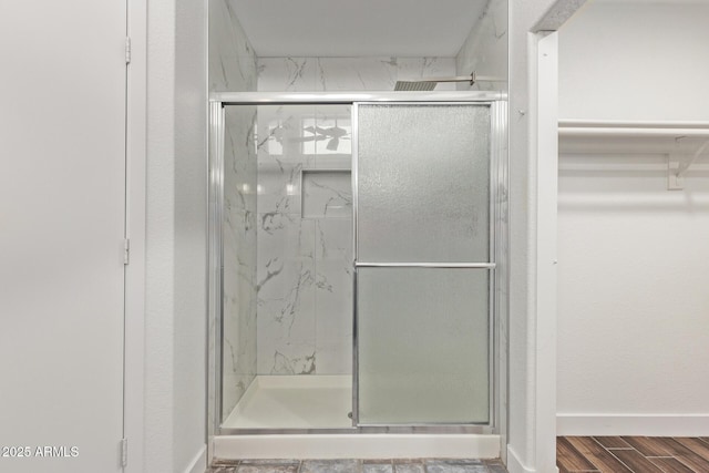 full bathroom with wood finished floors, baseboards, and a marble finish shower