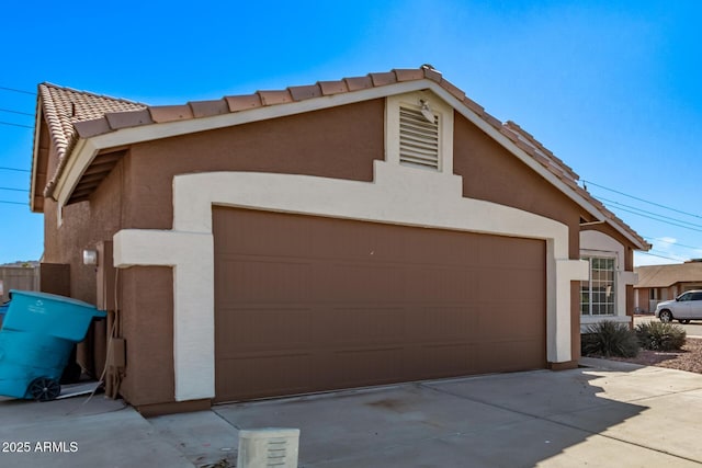 exterior space featuring stucco siding, a tile roof, and a garage