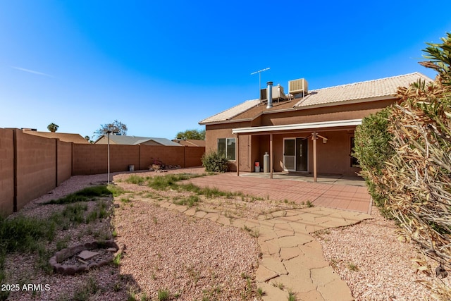 back of house with stucco siding, central air condition unit, a fenced backyard, ceiling fan, and a patio area