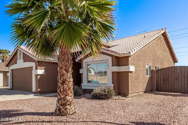 view of front facade featuring stucco siding, concrete driveway, a tile roof, and a garage