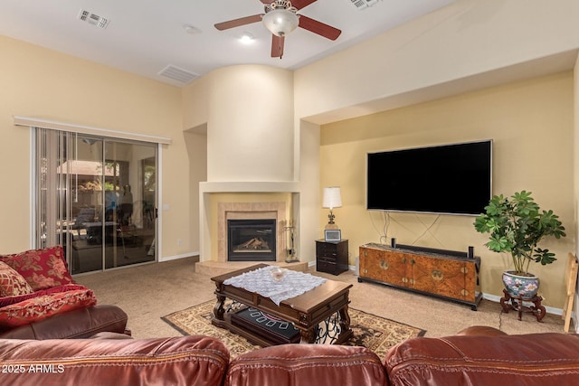 living room with carpet floors, baseboards, visible vents, and a tiled fireplace