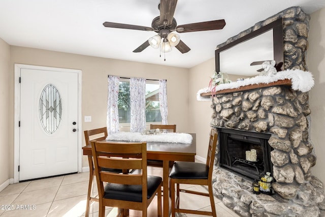 tiled dining area featuring ceiling fan and a fireplace