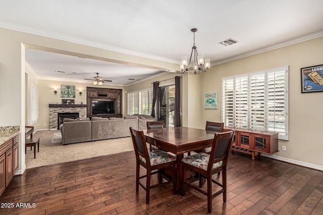 4463 S Oregon Ct, Chandler, AZ 85248 - dining area featuring a stone fireplace, dark wood finished floors, crown molding, a chandelier, and a ceiling fan