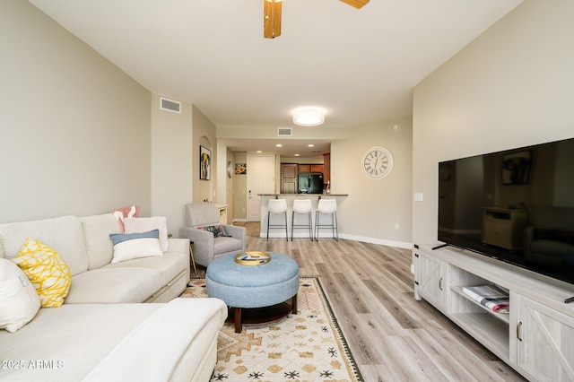 living area featuring visible vents, light wood-style flooring, and baseboards