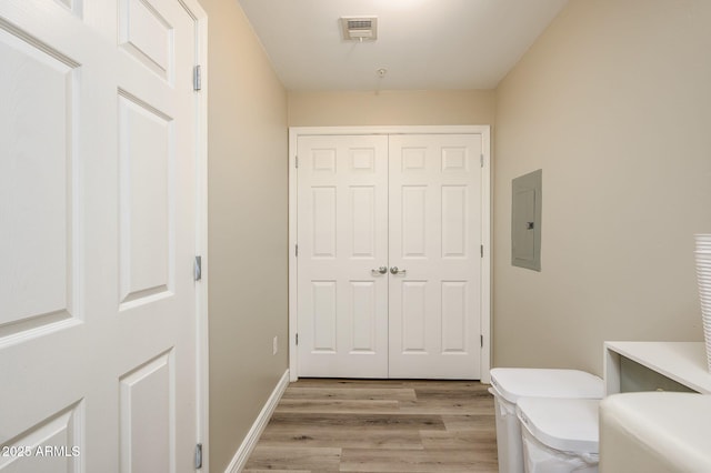 half bath featuring visible vents, toilet, electric panel, wood finished floors, and baseboards