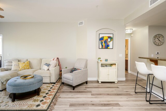 living area featuring light wood finished floors, visible vents, and baseboards