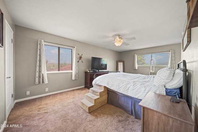 bedroom featuring multiple windows, ceiling fan, and light colored carpet