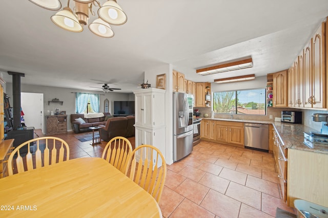 kitchen featuring appliances with stainless steel finishes, ceiling fan with notable chandelier, tasteful backsplash, and plenty of natural light