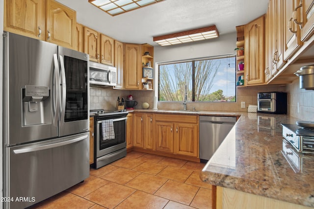 kitchen with appliances with stainless steel finishes, backsplash, light tile patterned floors, and sink