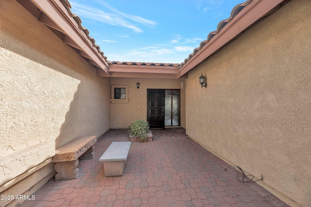 view of exterior entry with a patio area