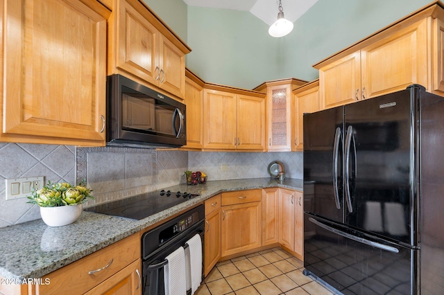 kitchen featuring light stone counters, vaulted ceiling, hanging light fixtures, light tile patterned floors, and black appliances