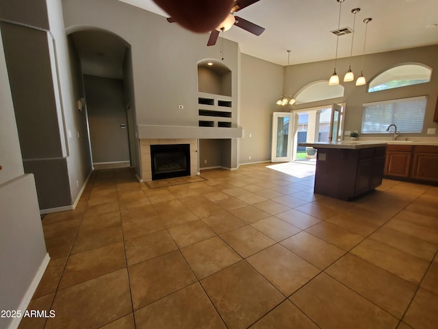351 S Apache Dr, Chandler, AZ 85224 - kitchen featuring light countertops, light tile patterned floors, built in shelves, a tiled fireplace, and ceiling fan