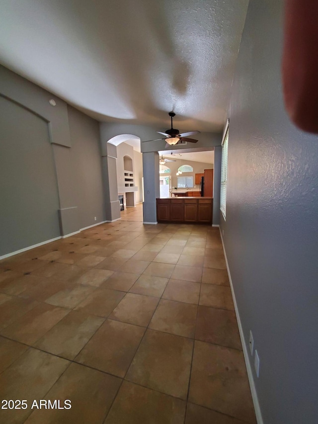 351 S Apache Dr, Chandler, AZ 85224 - unfurnished living room featuring ceiling fan, arched walkways, light tile patterned flooring, baseboards, and a textured ceiling