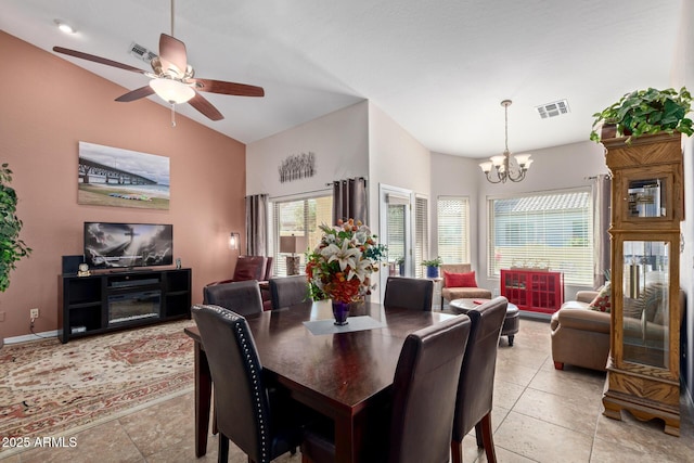 dining space with light tile patterned flooring, ceiling fan with notable chandelier, a healthy amount of sunlight, and lofted ceiling