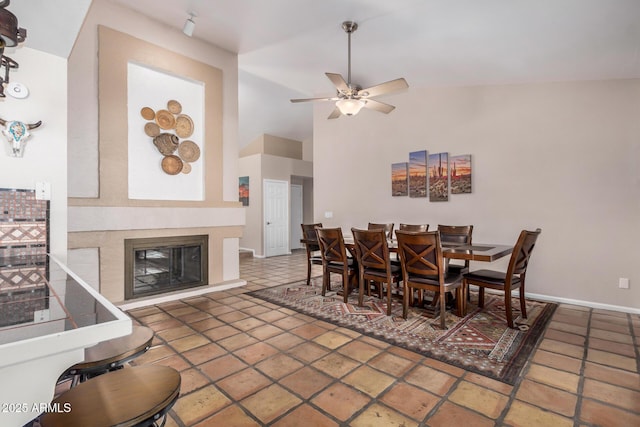 6118 E Star Valley St, Mesa, AZ 85215 - dining area featuring ceiling fan, a high ceiling, baseboards, tile patterned floors, and a glass covered fireplace