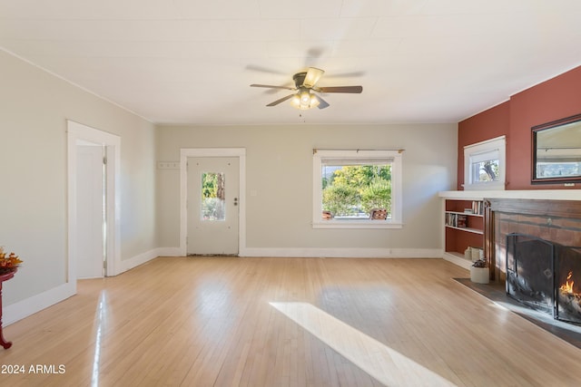 living room featuring a ceiling fan, a fireplace, baseboards, and wood-type flooring