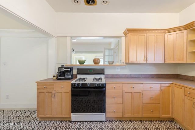 kitchen featuring open shelves, light brown cabinetry, gas range oven, and light countertops