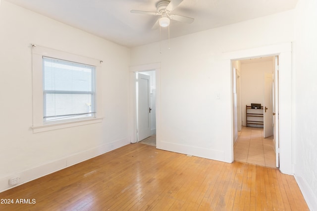 empty room with ceiling fan, light wood-type flooring, and baseboards