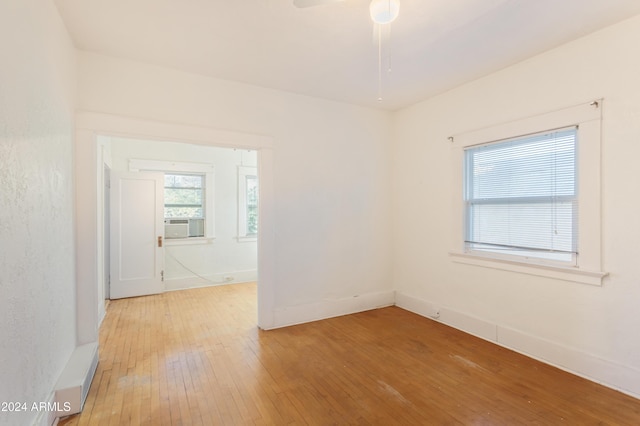 spare room featuring light wood-style flooring, a ceiling fan, and baseboards