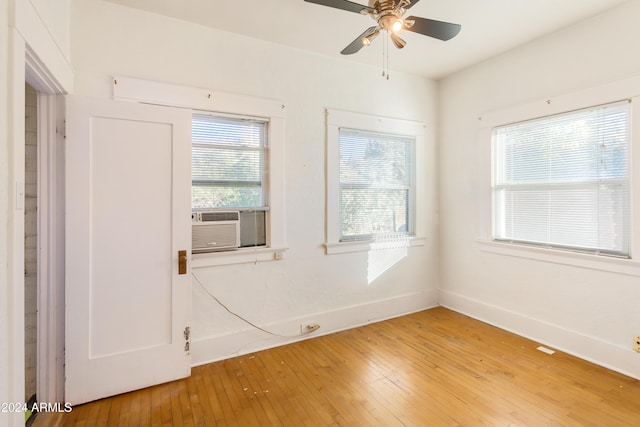 empty room with cooling unit, baseboards, a ceiling fan, and light wood finished floors