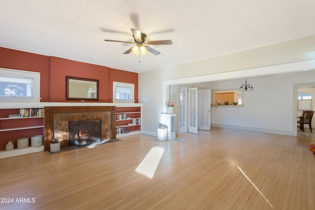 living area with ceiling fan, a fireplace, light wood-type flooring, and baseboards