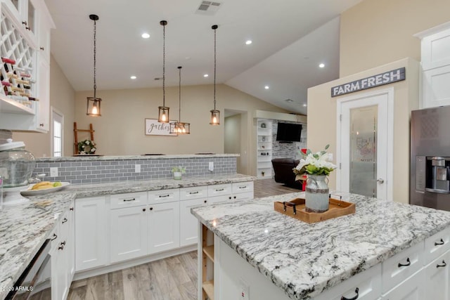 1101 S 4th St, Avondale, AZ 85323 - kitchen featuring decorative backsplash, light wood-style flooring, a peninsula, vaulted ceiling, and stainless steel appliances