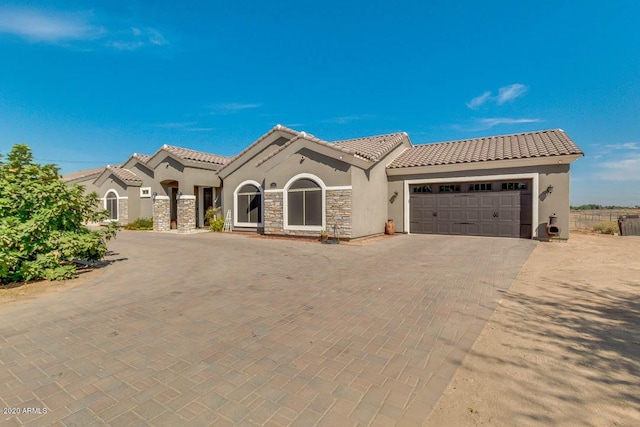 1101 S 4th St, Avondale, AZ 85323 - mediterranean / spanish-style house with stucco siding, decorative driveway, a tile roof, a garage, and stone siding