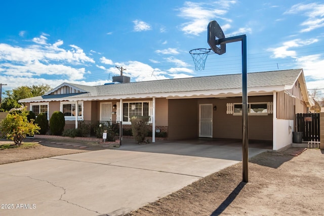 ranch-style house featuring covered porch, concrete driveway, an attached carport, and a shingled roof