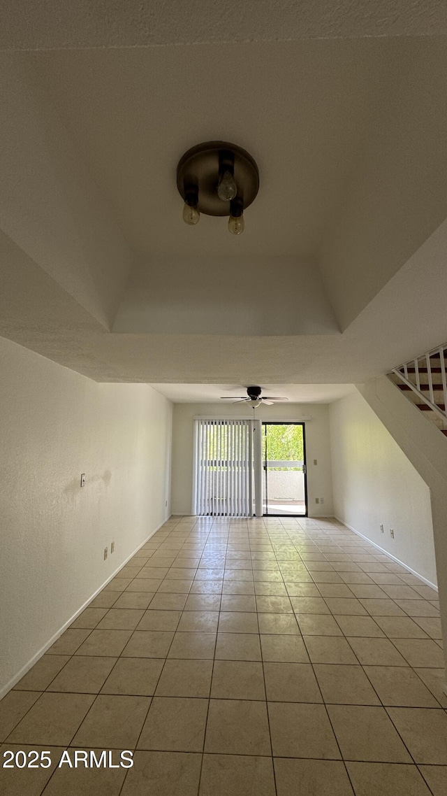 empty room featuring vaulted ceiling, light tile patterned flooring, baseboards, and ceiling fan