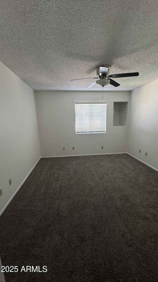 empty room featuring baseboards, a textured ceiling, ceiling fan, and dark carpet