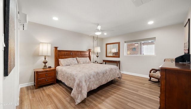 bedroom featuring light wood-type flooring, ceiling fan, and a wall unit AC