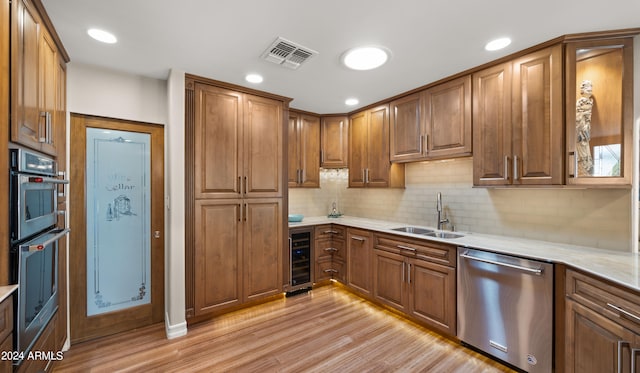 kitchen with appliances with stainless steel finishes, light hardwood / wood-style floors, wine cooler, and sink