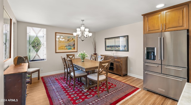 dining space with light hardwood / wood-style flooring and an inviting chandelier